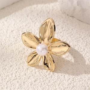 Detail of a golden flower open ring with textured petals and a centered white pearl inlay
