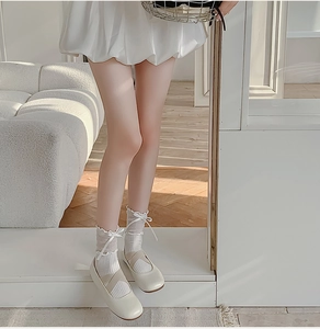 Close-up of white Mary Jane shoes paired with lace bow socks in a soft home setting