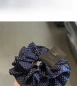 Detail eines dunkelblauen Haargummis mit weißen Punkten und Made in Korea Etikett