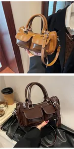 Detail view of stylish leather barrel bags in caramel and dark brown with front pockets