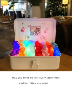 Detail of colorful LED glowing hair scrunchies stored in a cream-white honey buckle box
