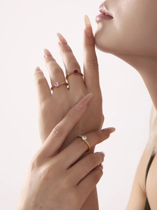 Detailed view of three stackable gold rings featuring red, pink and white stones