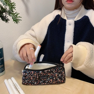 Floral corduroy pencil case shown in use, featuring a pink and blue flower pattern