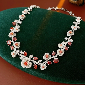 Close-up of vintage silver rose necklace with red and clear zircon on velvet stand
