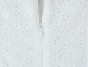Close-up of white hollow embroidery fabric and high-quality invisible zipper detail