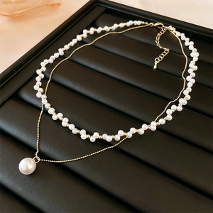 Collana a doppio strato con perle barocche e perle dorate su espositore in pelle nera