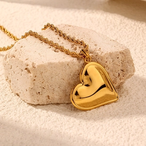 Elegant gold stainless steel heart pendant on a twisted rope chain over soft stone