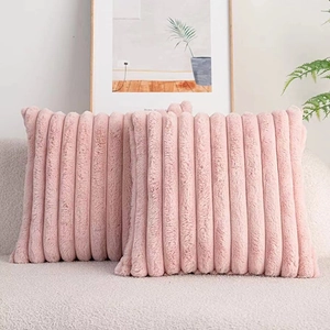 Detail of two pink faux rabbit fur pillows with stripe texture on a beige sofa