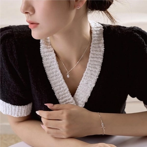 Close-up of model wearing silver necklace and bracelet set with rectangular crystals