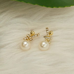Elegant gold twisted hoop earrings with champagne pearls on white fur background