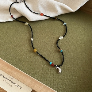 Macro view of multi-color beaded necklace with a silver croissant pendant and lobster clasp