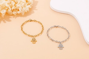 Detailed macro view of gold and silver Hamsa Hand bracelets with elegant Figaro chain links
