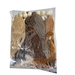 Macro detail of DIY kit including natural wood beads and colorful cotton tassels in a polybag