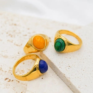 Detailed view of three vintage gold signet rings with orange, green, and blue stones
