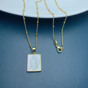 Close-up of Guadalupe pendant with S925 hallmark on gold chain with white mother of pearl