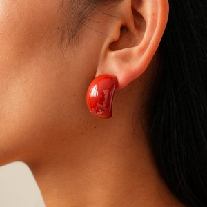 Close-up detail of glossy dark red drop earrings in a minimalist organic resin design