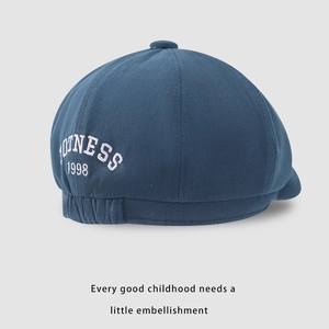 Detail view of children's navy beret featuring OUTNESS 1998 embroidery and elastic strap