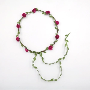 Detail of adjustable floral headband with pink roses and green leaves on brown rattan