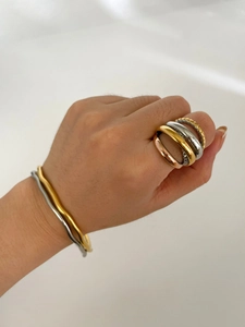 Detailed view of tricolor layered rings and wavy bracelets in gold, silver, and rose gold