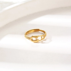 Minimalist gold paperclip safety pin adjustable open ring on a wavy textured surface