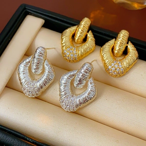 Detailed view of U-shaped gold and silver earrings with twisted texture and pave crystals