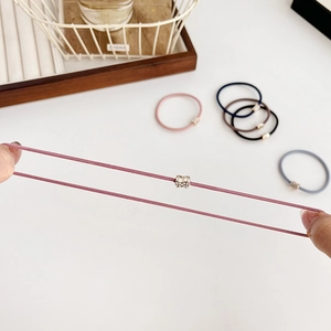 Elastic hair ties in various colors with metallic accents and high stretch shown by hand