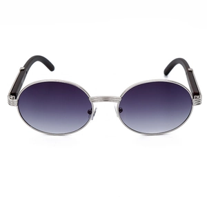 Detalle de gafas de sol ovaladas plateadas con lentes degradadas y patillas de madera