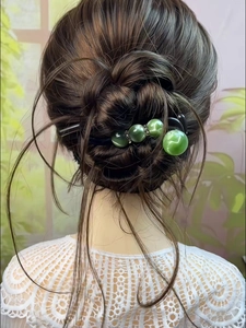 Detail view of acrylic hair clip with green cat-eye beads and sparkling rhinestones