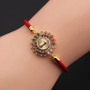 Detail of red braided religious bracelet with gold Virgin Mary pendant and zircons