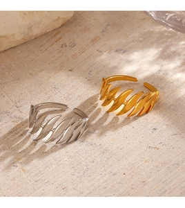 Close-up of 18K gold and silver plated feather design open rings on stone texture