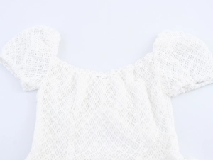 Detail of white lace dress showing off-shoulder neckline and puff sleeve texture