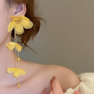 Detail of yellow fabric floral tassel earrings showing elegant drape on model