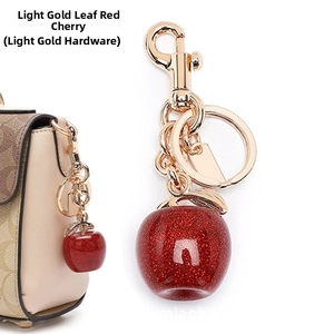 Detail of red glitter cherry keychain with gold leaves on a luxury handbag strap