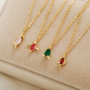 Close-up of four dinosaur necklaces with pink, red and green gemstone pendants in 18K gold