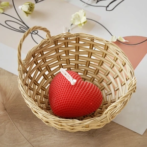 Dettaglio candela a cuore rosso con texture a nido d'ape in cesto di vimini