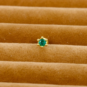 Macro shot of gold-plated screw-back stud featuring a six-prong set green zircon stone
