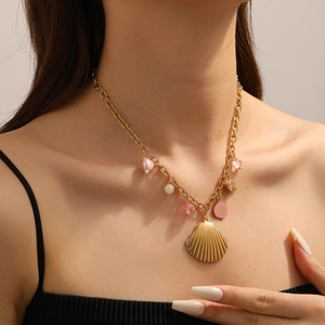 Detailansicht einer goldenen Kette mit Muschelanhänger und rosa Sternen am Hals getragen