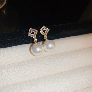 Detail of gold plated diamond diamond-encrusted pearl earrings with rhombus geometric design