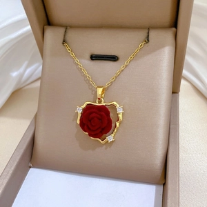 Macro detail of red flocked rose heart pendant with gold wave edge and crystal accents