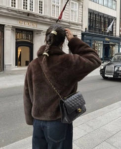 Brown faux fur jacket styled with a black quilted chain bag in a city street setting