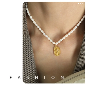 Close-up of elegant freshwater pearl necklace with vintage gold tulip relief pendant