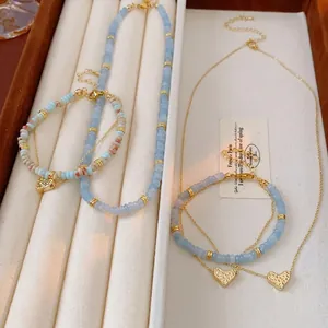 Blue beaded heart necklace and bracelet set with gold pendants on a velvet tray