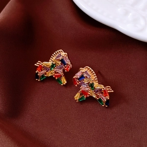 Close-up of 18K gold plated pony earrings with colorful gemstones on brown silk