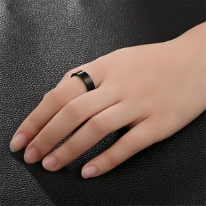 Close-up of matte black 6mm stainless steel flat ring worn on a finger over leather