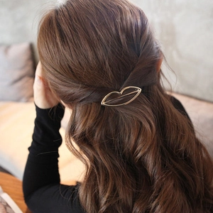 Elegant gold metal lip shaped hair clip accessory styled on brown wavy hair