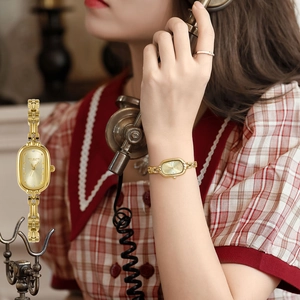 Close-up of vintage golden tonneau quartz watch with a unique metallic chain strap