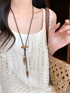 Gros plan d'un collier long bohème avec perles en céramique et pendentif en bois sur un modèle