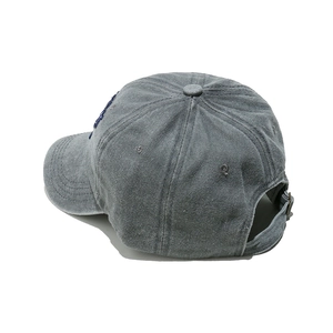 Detail view of washed grey cotton baseball cap showing blue side embroidery and metal buckle