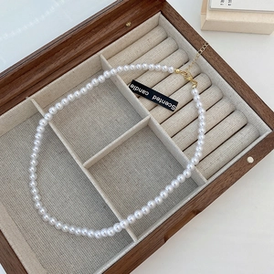 Detail of elegant white pearl necklace with gold clasp in a wooden jewelry box