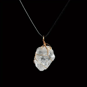 Detail of wire-wrapped natural clear quartz crystal pendant on black woven cord